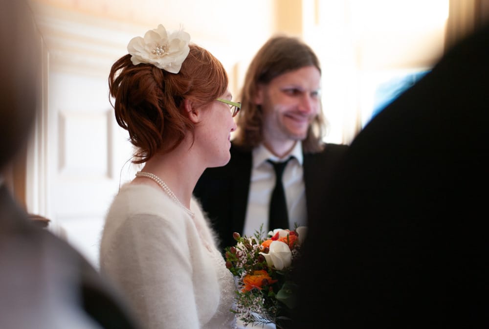 Bride Catherine chatting warmly with guests inside Weetwood Hall, faux flower hairpiece and white cardigan.