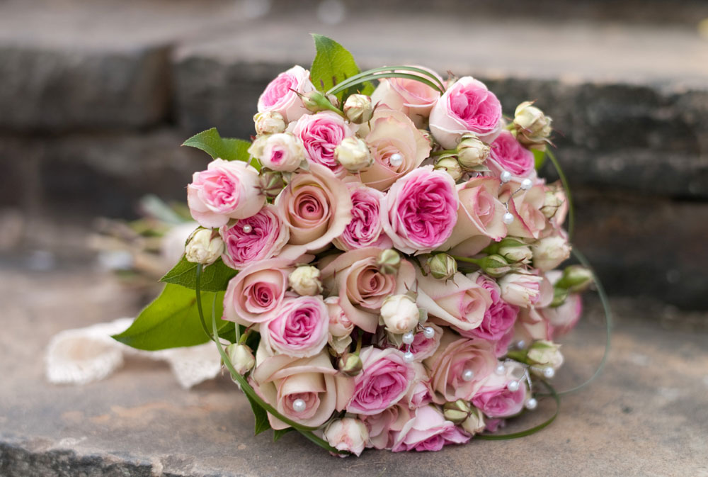Dani’s bridal bouquet with soft pink and cream flowers on the stone steps
