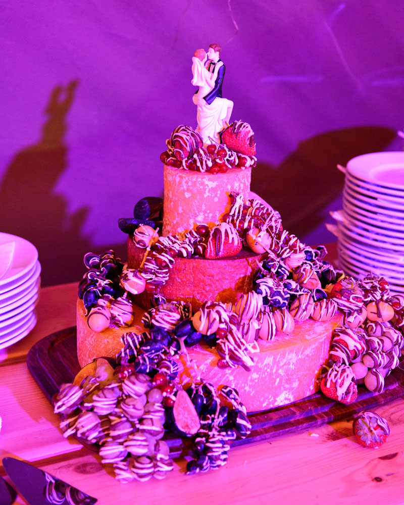 Inside the Papakata tent: a stacked ‘cheese’ wedding cake glowing pink under the lights.