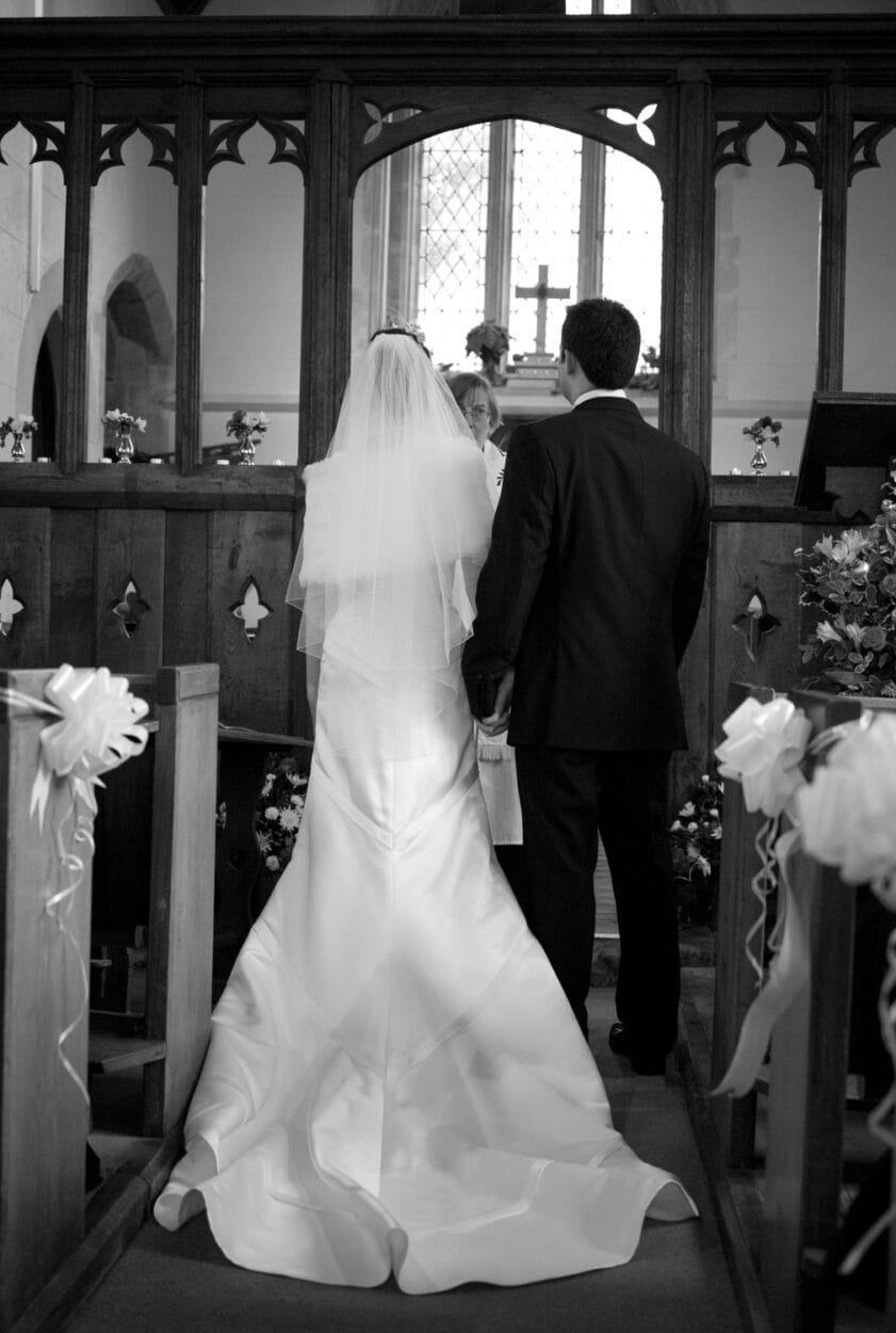Couple stand at the altar receiving a blessing.