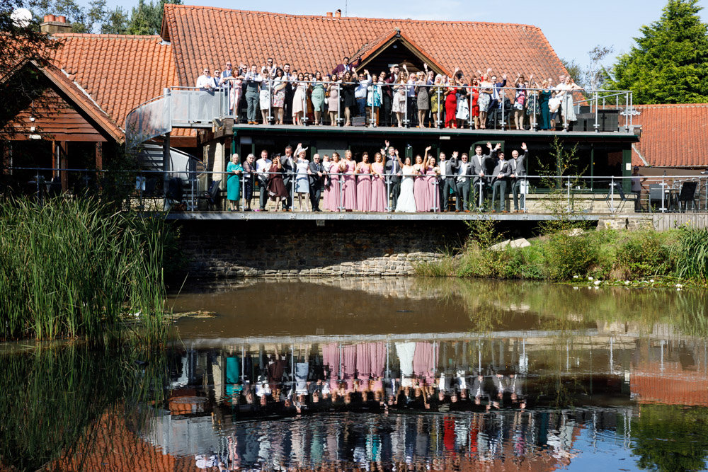 Group photo of all guests on the balcony at Chevin, with reflections in the still water below.