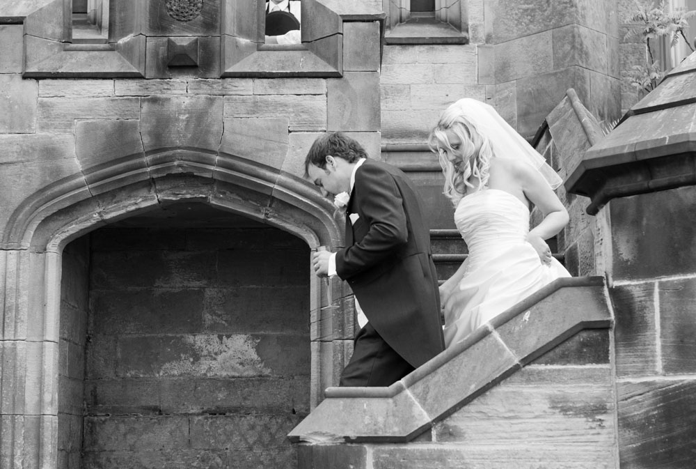 The couple walk down stone steps into the courtyard where guests await