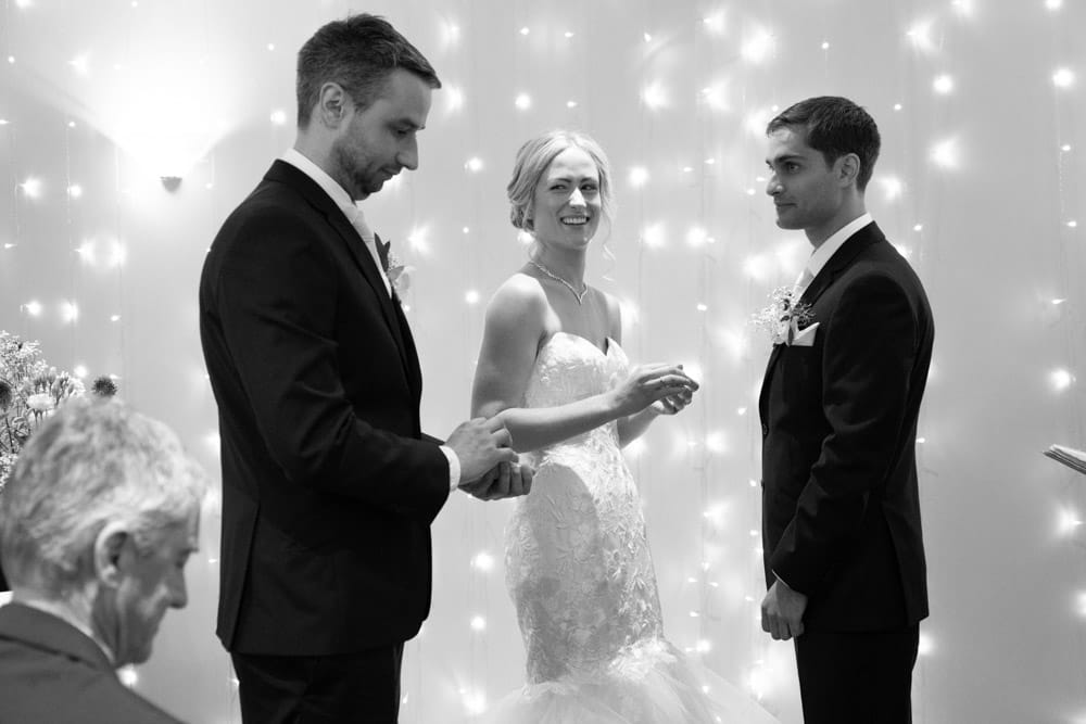 Best man presents the ring box to Helen, who smiles warmly.