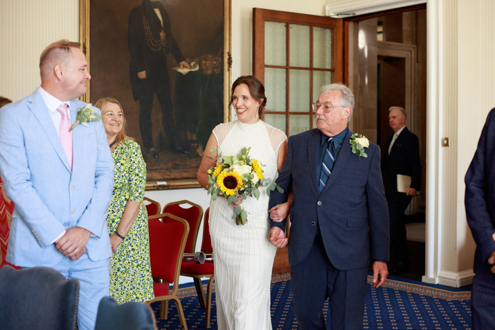 Bride enters Civic Hall with big smiles from both bride and groom