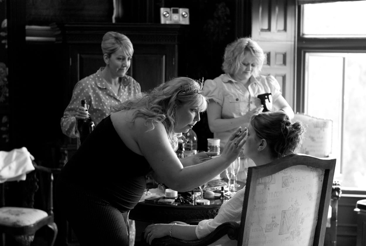 Nikki helping a bridesmaid apply makeup during morning preparations.