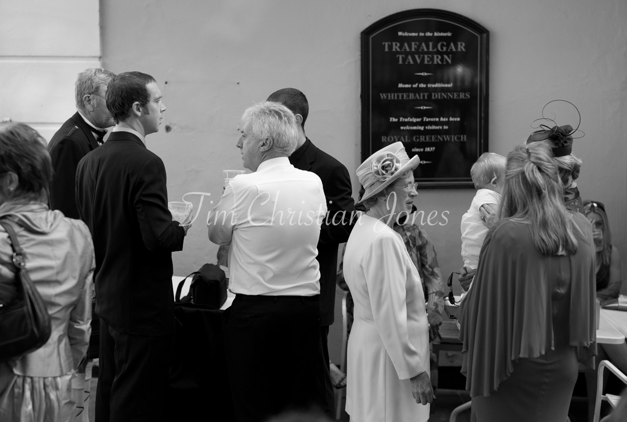 Black and white image of guests mingling outside with the Trafalgar Tavern plaque visible in the background.
