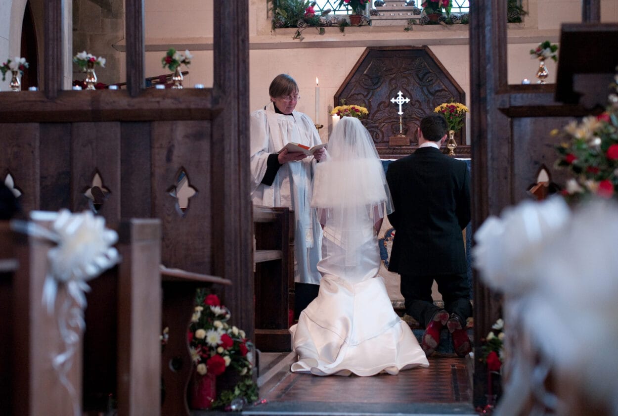 The couple kneel at the altar as the vicar speaks.