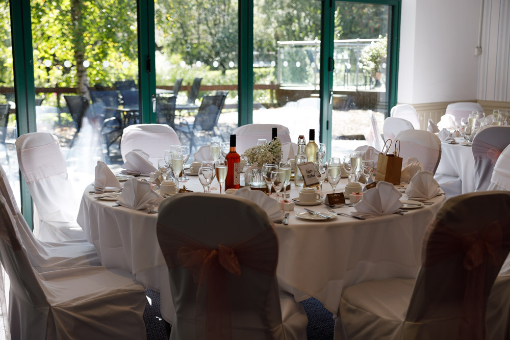 The Chevin Lodge wedding breakfast room filled with sunlight and views of green woodland.