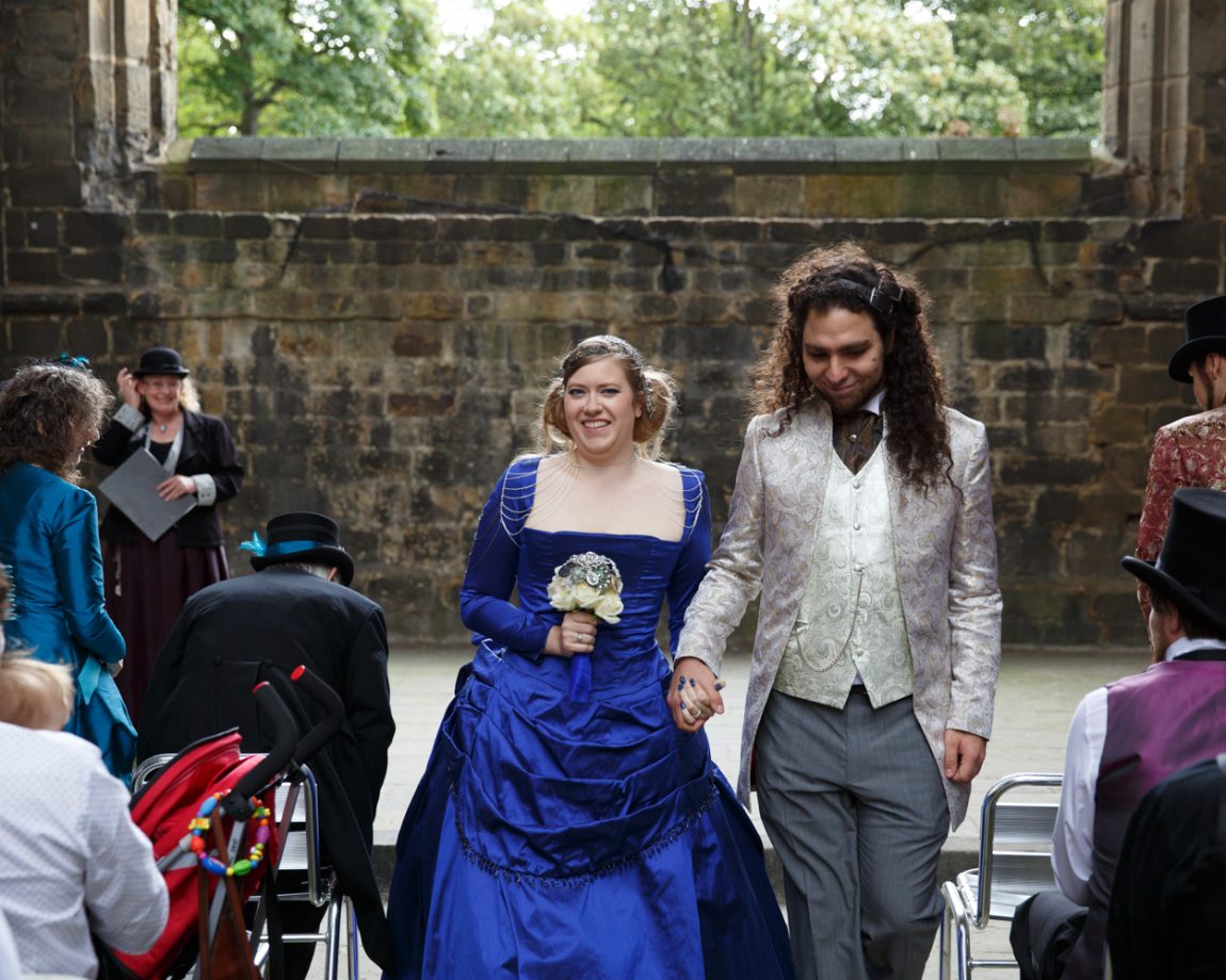 060 the couple exit walking down past the guests sat clapping kirkstall abbey wedding linsey and chris