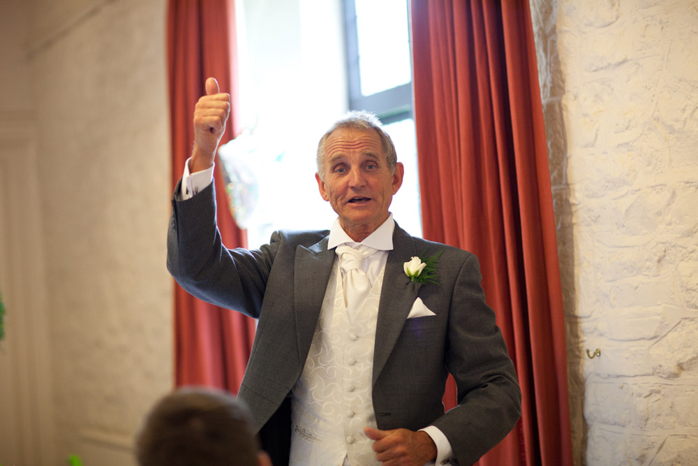 Father of the bride stands to begin his speech at the top table
