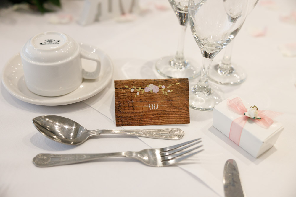 Kyra’s personalised name card on the wedding table, soft white card with natural detailing.