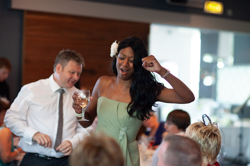 Bridesmaid throws a joyful fist pump in the air during the reception, caught in the moment.
