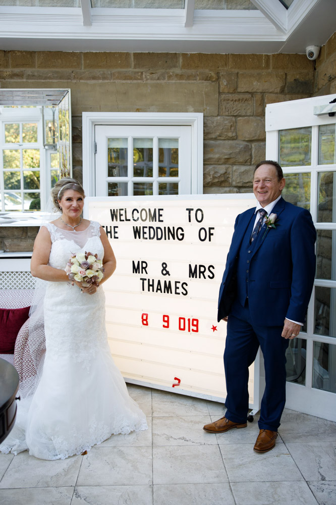 The couple stood inside beside their "Welcome to the wedding of" sign