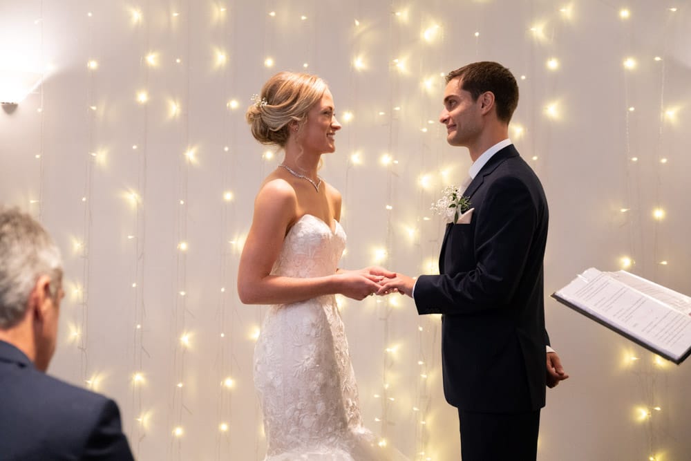 Close-up of Helen gently placing the ring on Adam’s hand.