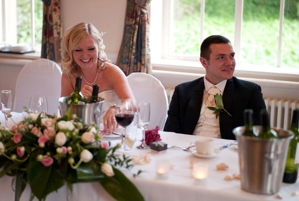 Scott listens with a soft smile as Dani laughs during the wedding speeches