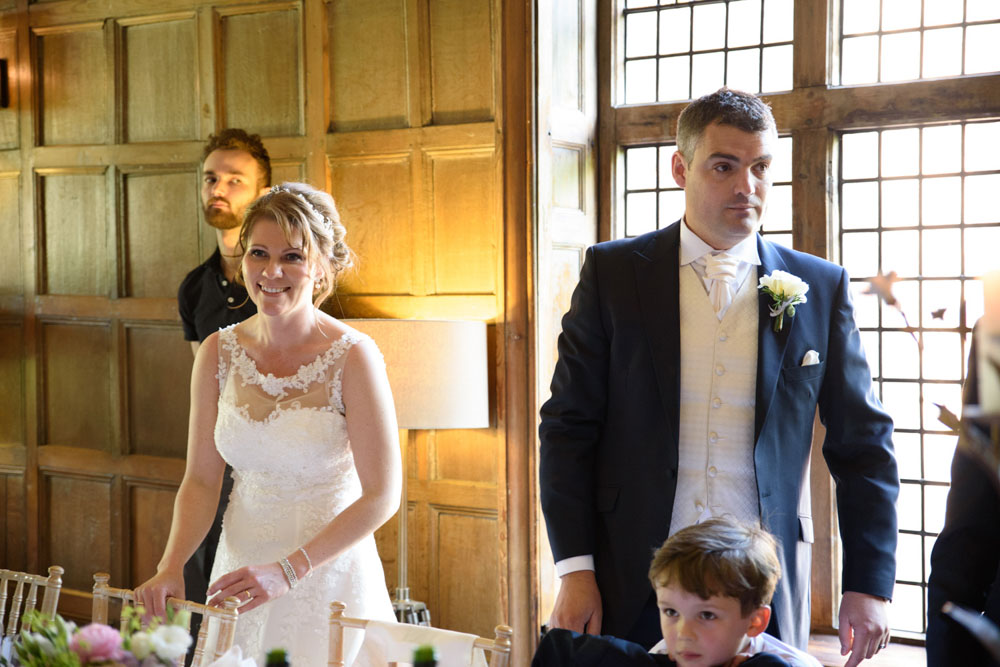 Wedding guests inside cheer as the couple arrive at the top table.