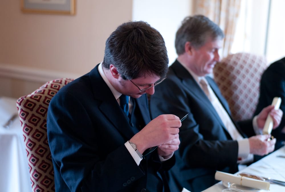 Best man smiling while reading speech notes during Weetwood Hall wedding breakfast.