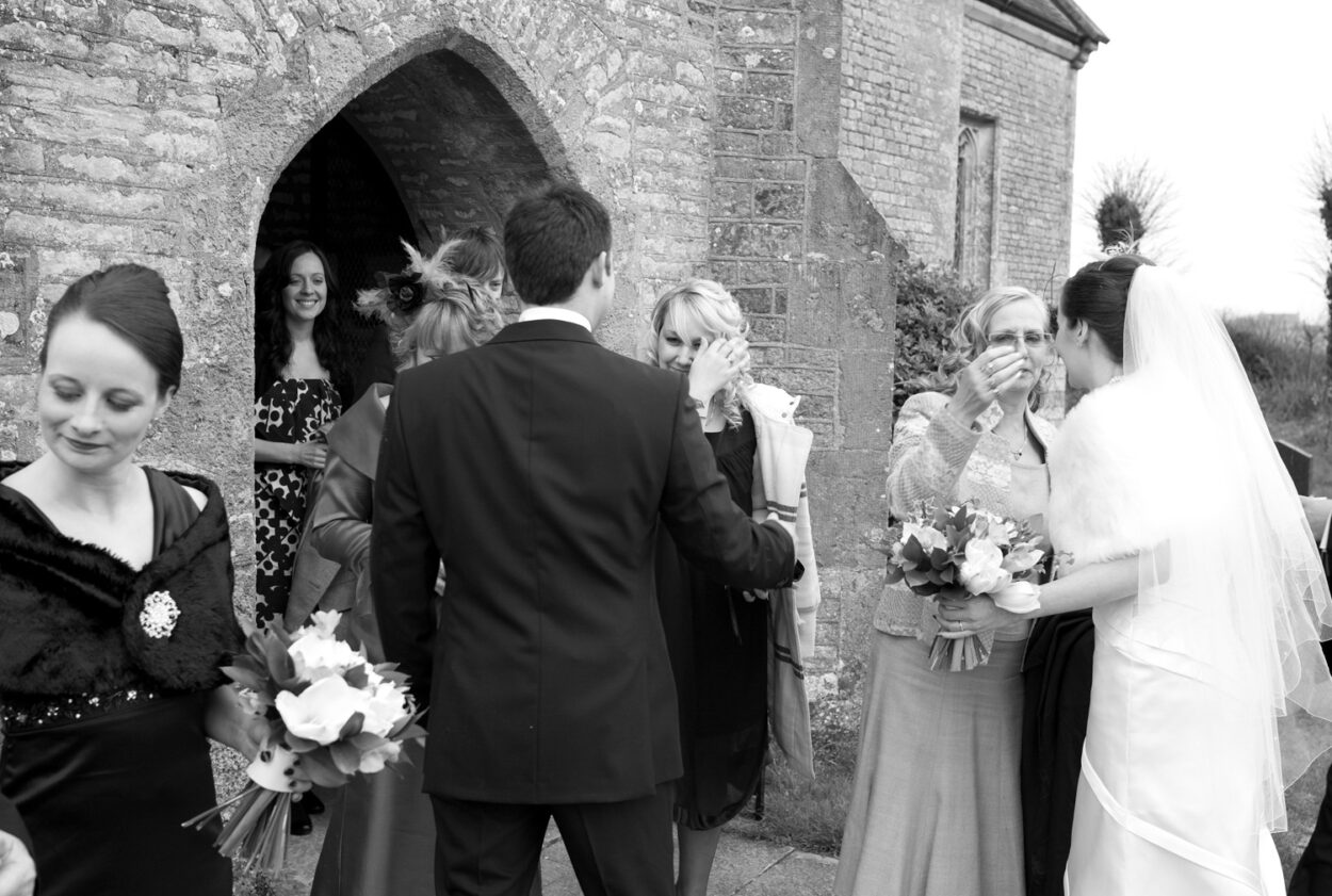 Groom’s sister smiles proudly at her brother outside the church.