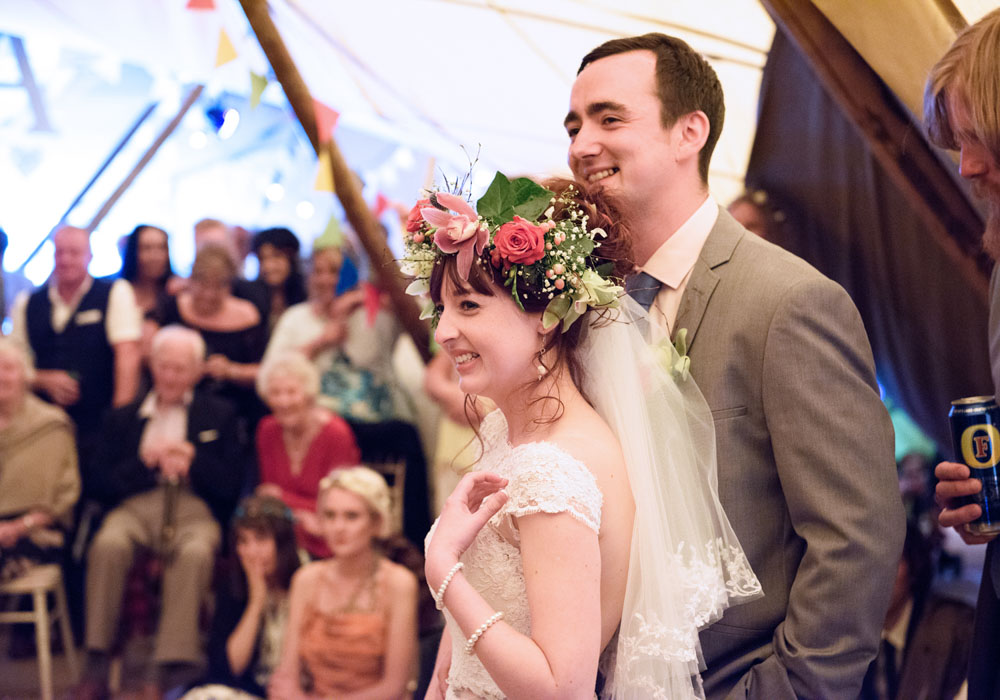 Bride and groom smiling and reacting during the first wedding speech.