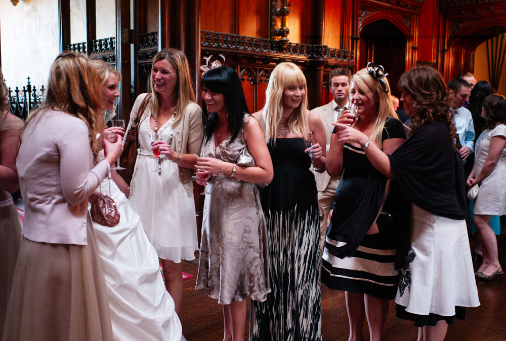 Bridesmaids and friends gathering indoors in golden light for a group photo