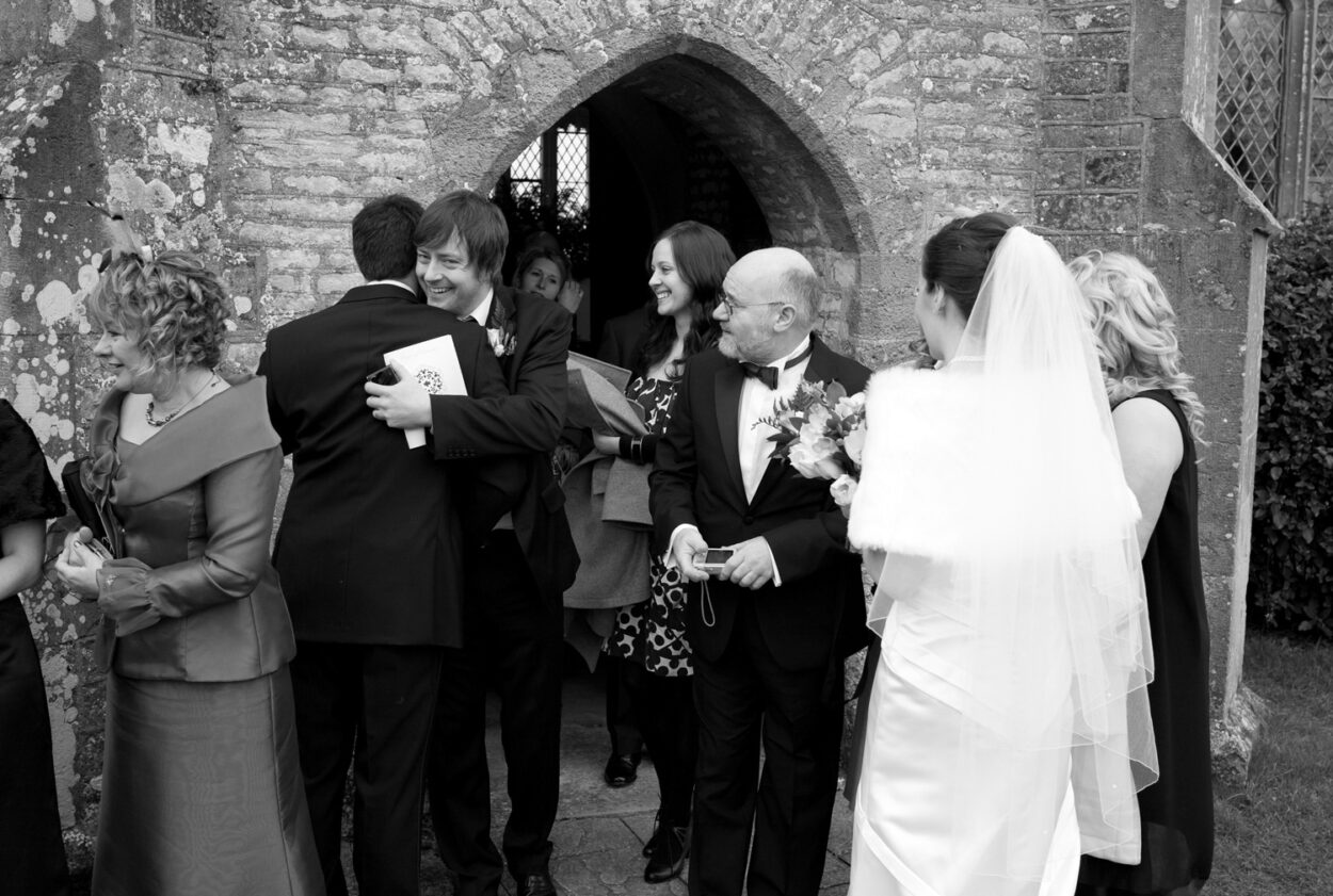 Friends hug the groom outside the church.