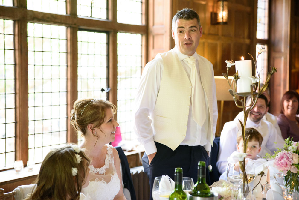 Groom speaks as the bride smiles beside him during speeches.