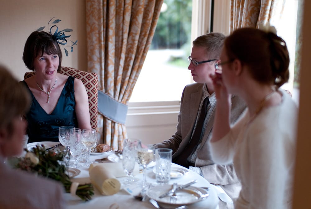 Round top table at Weetwood Hall, bride and groom chatting naturally with guests.