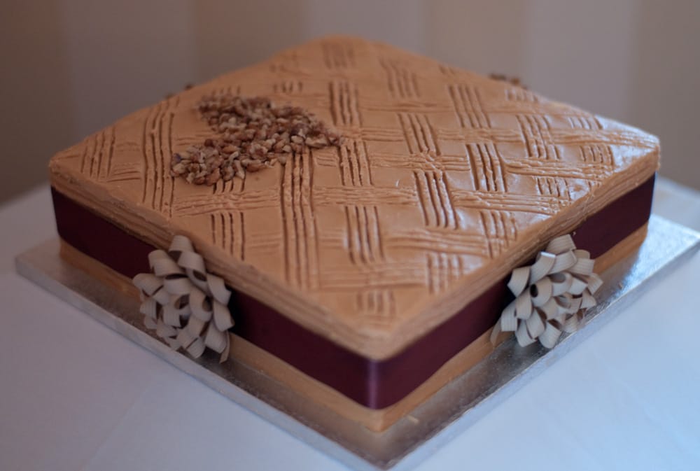 Coffee and walnut wedding cake with ribbon rosettes, displayed at Weetwood Hall Leeds.