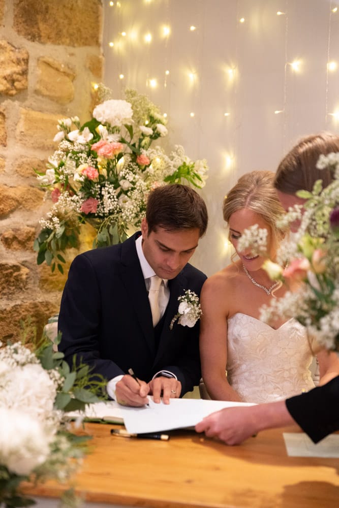 Adam signs the wedding register while Helen watches closely.