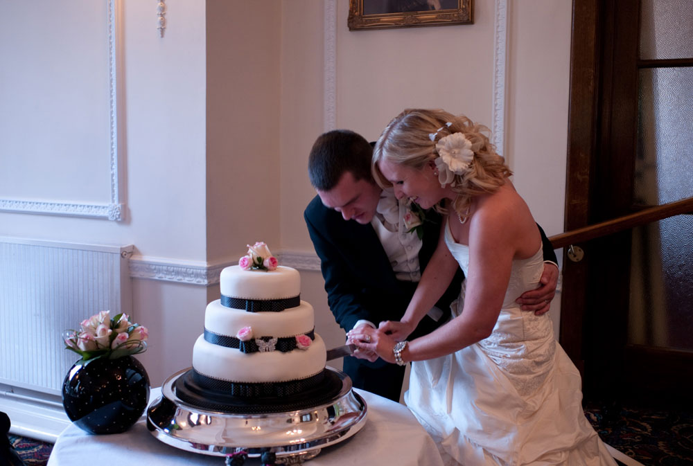 Dani and Scott begin cutting into the bottom tier of their wedding cake