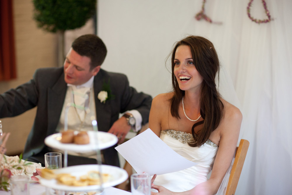 Lowri laughs and Tim covers his mouth, amused