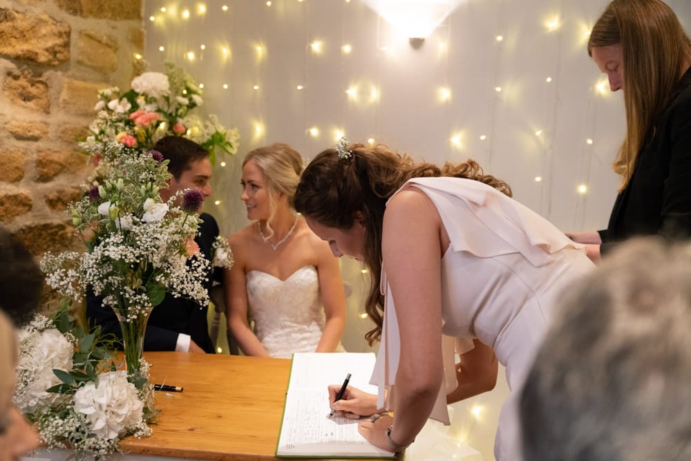 Bridesmaid steps forward to sign as a witness.