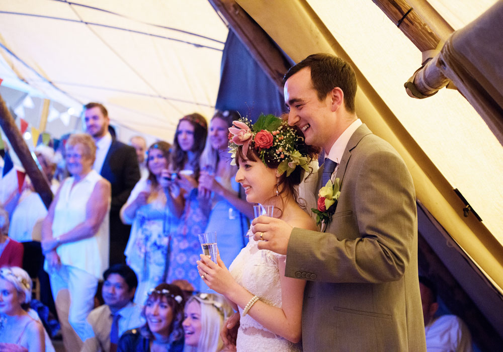 Bride and groom smile, slightly embarrassed by the slideshow.
