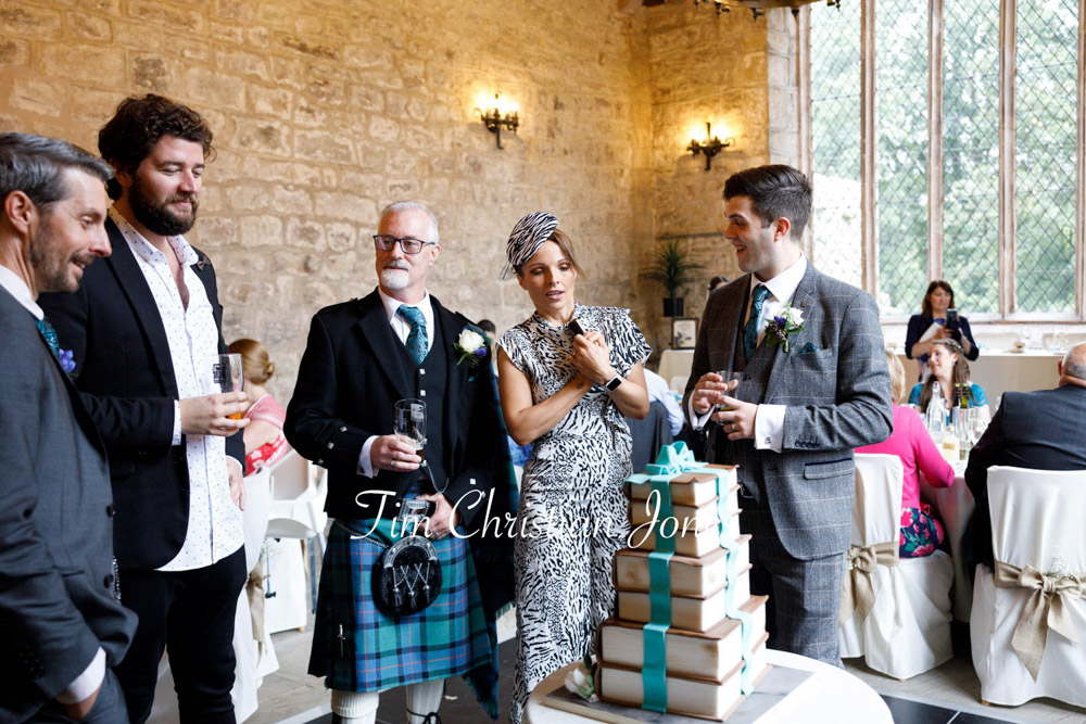 Smiling guests gather around the wedding cake at Barden Tower.
