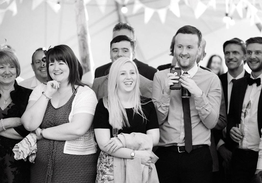 Guests react with smiles and laughter to the slideshow in the tent.
