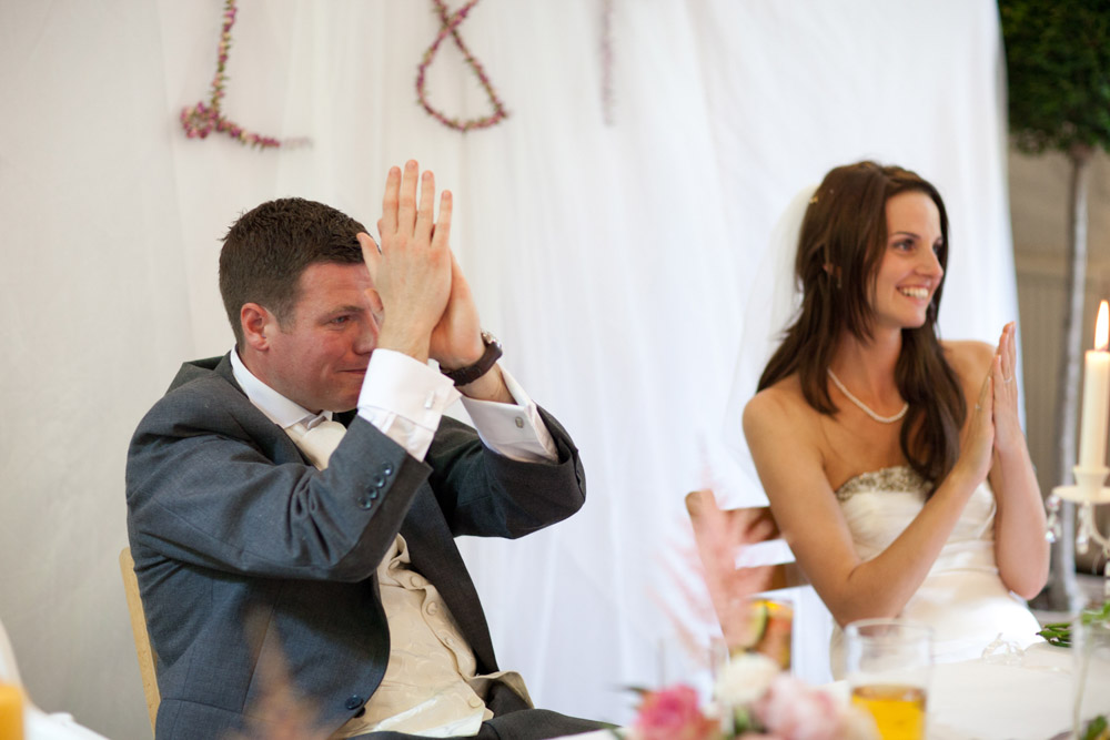 Bride and groom applauding during the best man’s speech