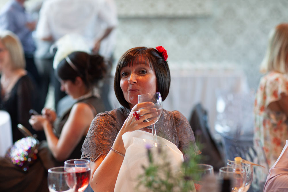 A guest lifts her wine glass and poses as she notices the camera.
