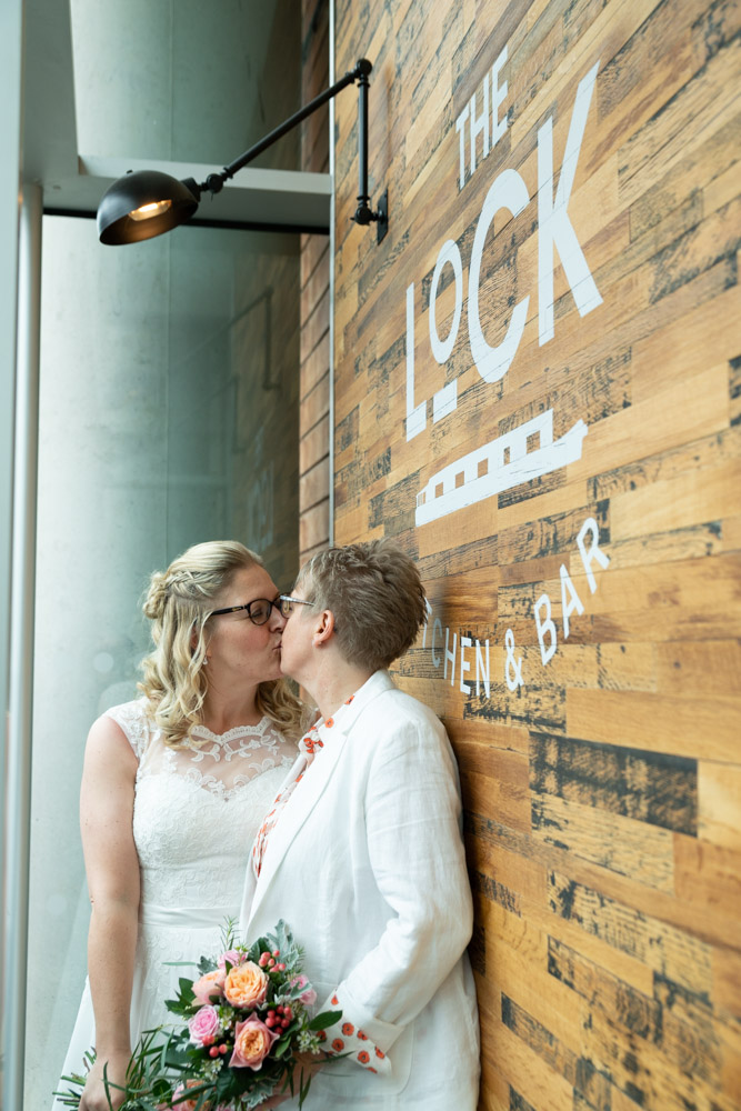 Clare and Tracey share a kiss against the timber facade