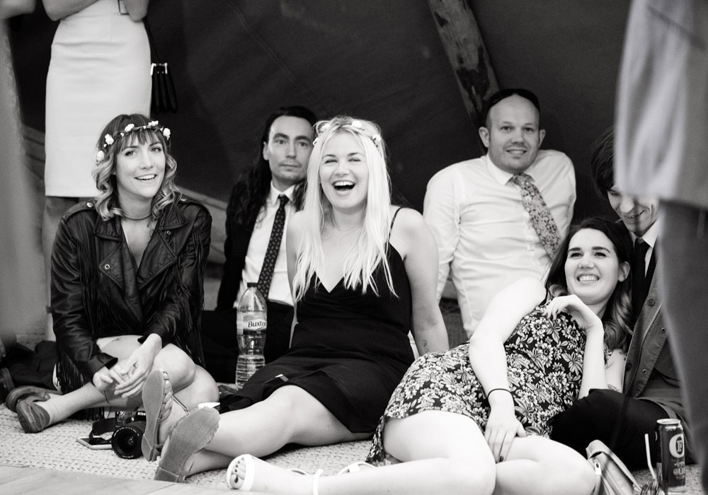 Guests sit casually on the floor, laughing at the wedding slideshow.