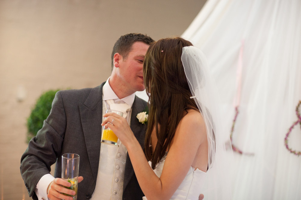Bride and groom kiss at the top table