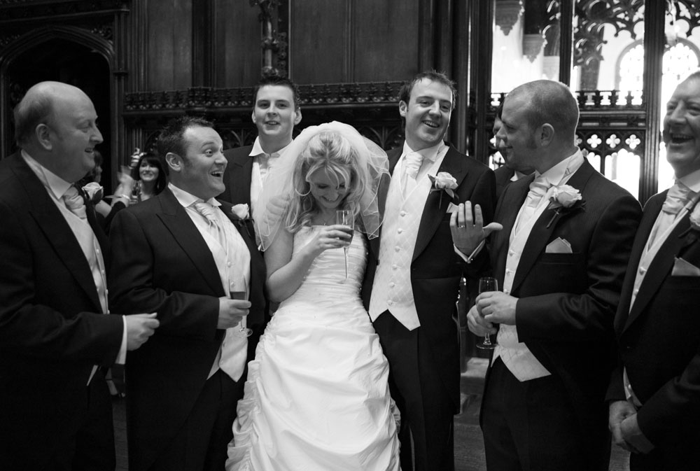 Vicky joins the groomsmen for a group photo, everyone smiling in black and white
