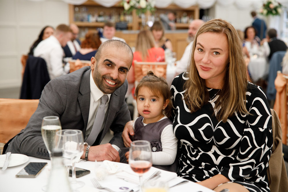 A family portrait with their young daughter smiling.
