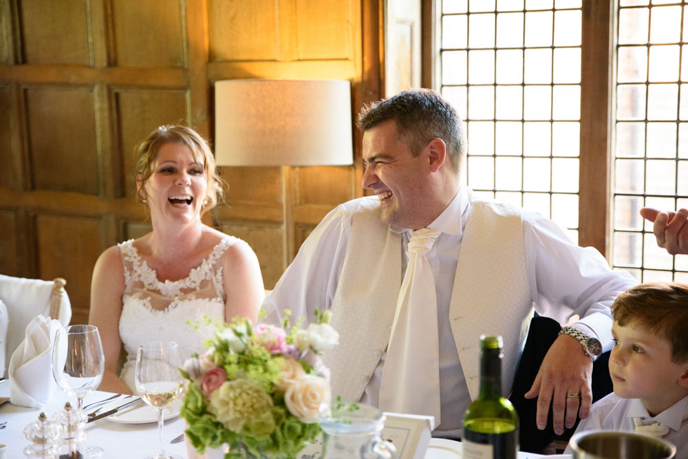 The couple laugh together as the best man’s speech continues.