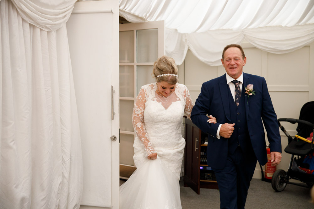 The couple walking into the marquee to applause.