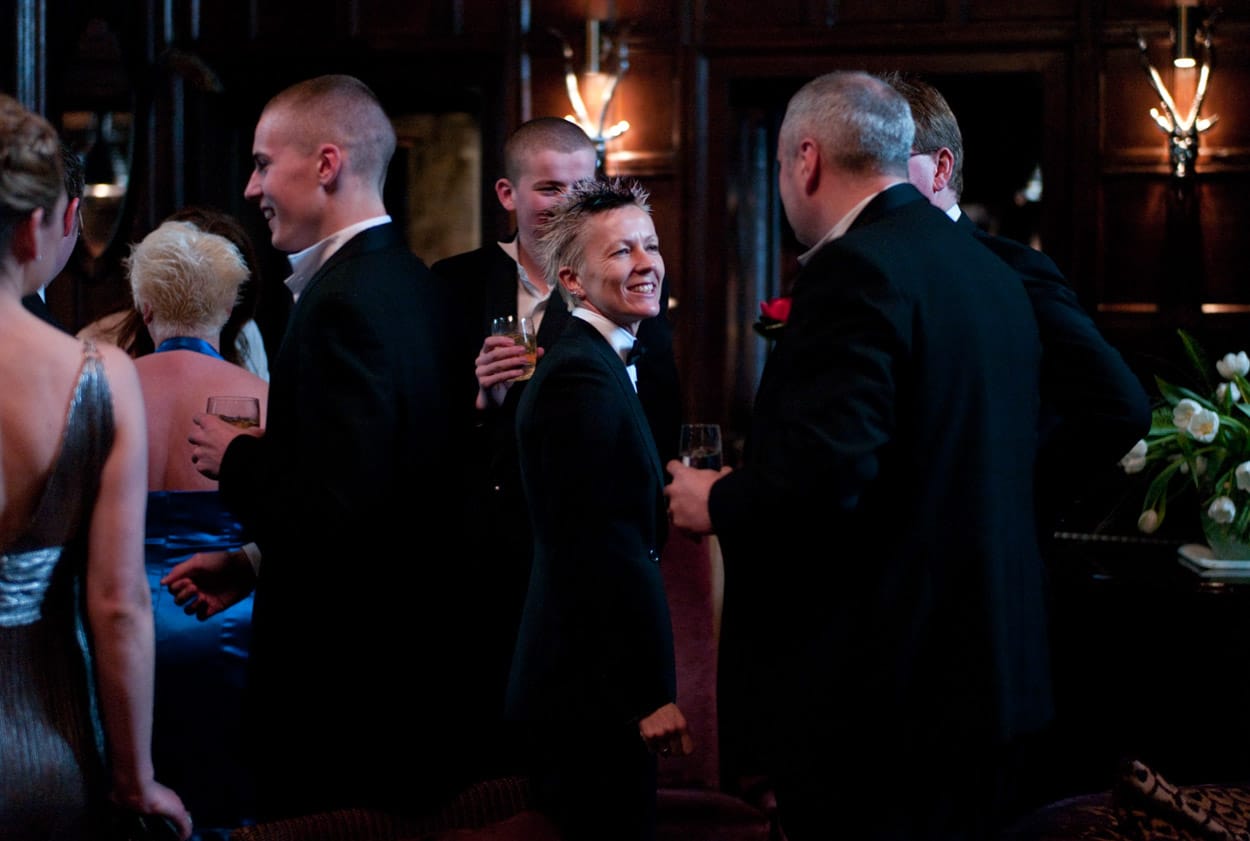 Groom and his sons chatting with guests in the warm honey-coloured ceremony rooms of Mitton Hall.