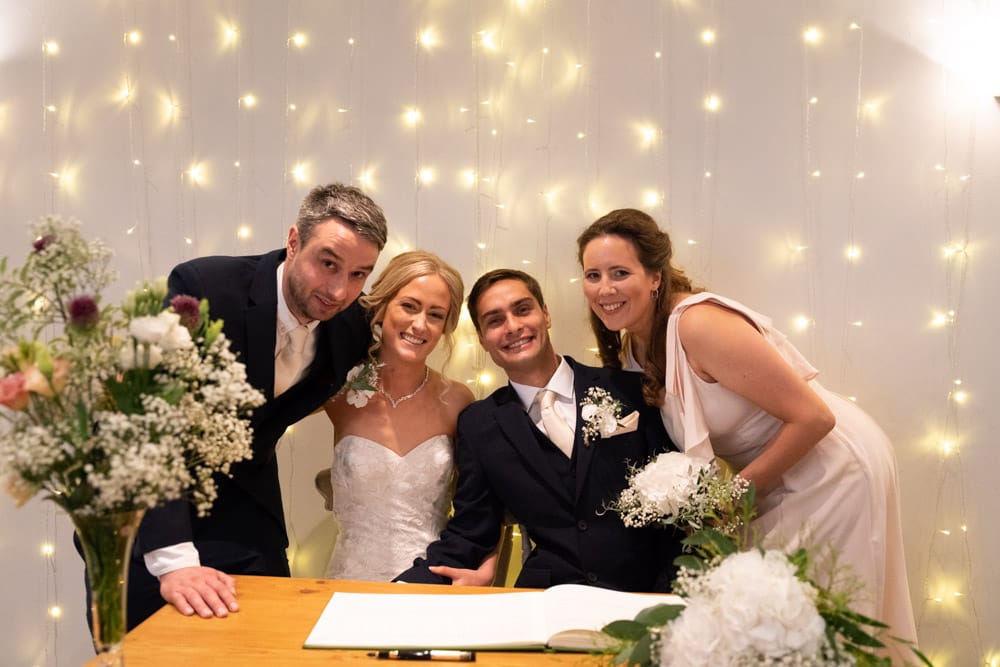 Couple and witnesses lean close together in a warm group pose.