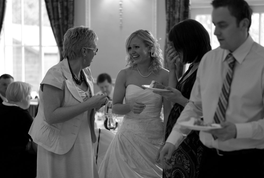 Black and white photo of Dani smiling with emotion as she connects with guests and family.
