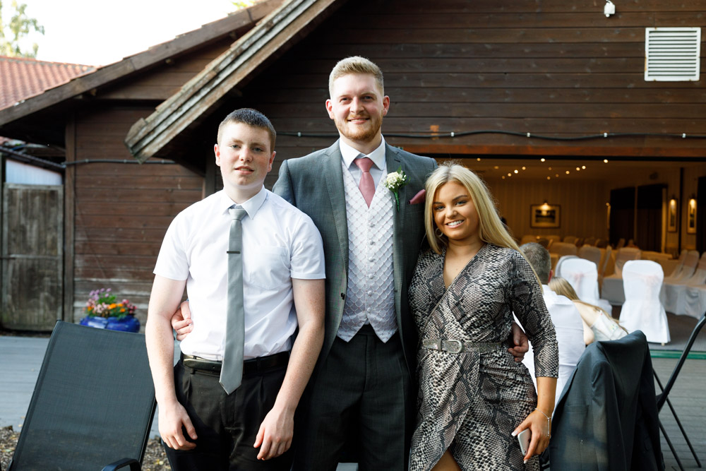 Matt shares a photo moment with two teenage family members, standing outdoors and smiling.