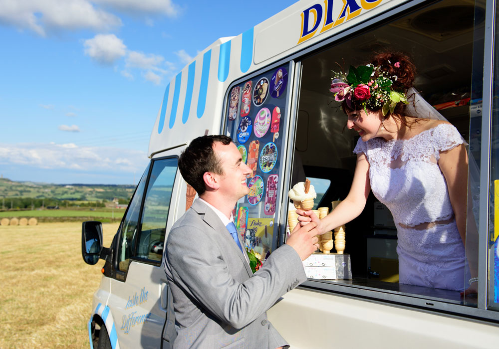 Bride Chloe stands in an ice cream van handing John a 99 Flake with sunshine behind.