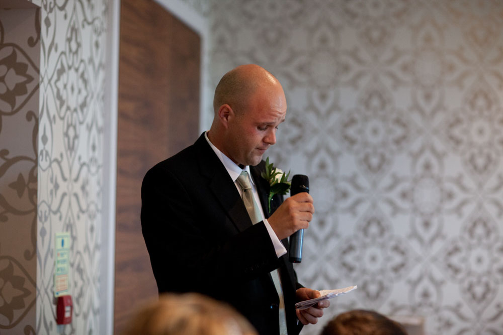 The best man stands confidently mid-speech, holding the room’s attention.